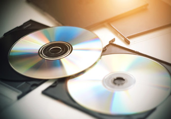 Two CDs for music, video and recording information, which are now less and less used out of use, lie on a white table, illuminated by sunlight.