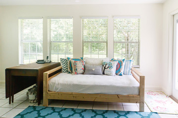 Boho Bohemian style futon seating area with white cushions and colorful pillows and lots of windows and natural light