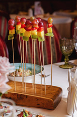 Assortment of canapes on wooden board. Banquet service with different food snacks and appetizers.. Catering food, snacks with strawberry, pineapple, fruit and berries. Party food concept.