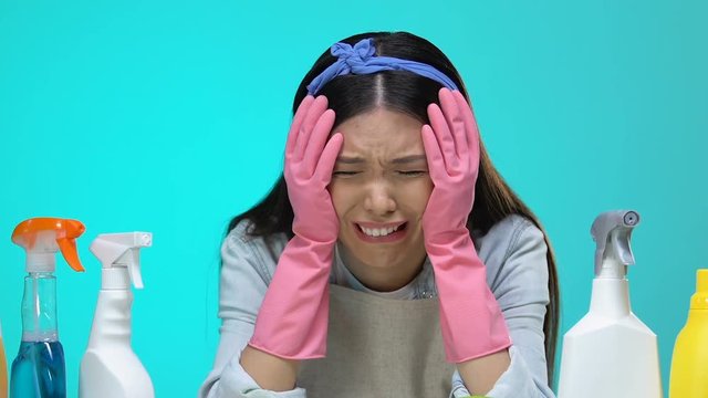 Housewife looking at detergents and crying, ineffective cleaning products