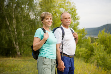 elderly couple with backpack on the mountain. Senior couple walking in nature. travel tourism concept