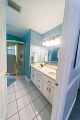 Bright blue colorful spacious master bathroom. with gold shower stall