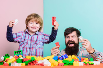 Dad and child build plastic blocks. Happy family. Child development and upbringing. Importance of playing together. Dad and son have fun. Childish cheerful dad and funny son. Dad play toys with kid