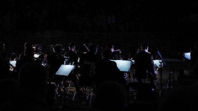 An evening concert of an open-air symphony orchestra in a city park.