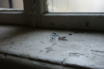 addiction concept. Syringe and needle on a dirty window sill at the entrance