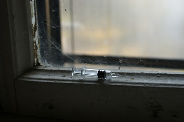 addiction concept. Syringe and needle on a dirty window sill at the entrance