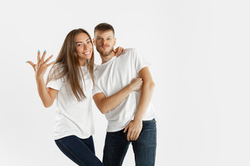 Beautiful young couple's portrait isolated on white studio background. Facial expression, human emotions, advertising concept. Copyspace. Woman and man standing crossing hands or dancing, look cool.