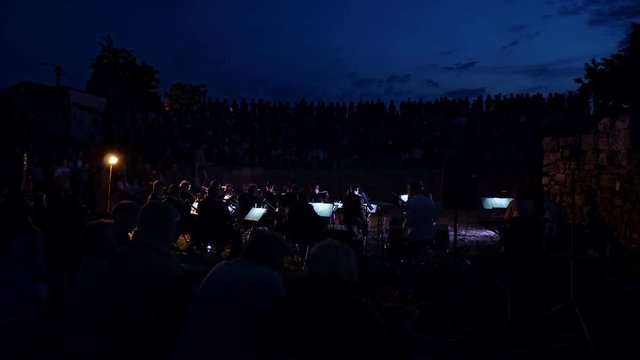 An evening concert of an open-air symphony orchestra in a city park.