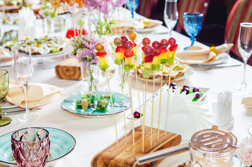 Assortment of canapes on wooden board. Banquet service with different food snacks and appetizers.. Catering food, snacks with strawberry, pineapple, fruit and berries. Party food concept.