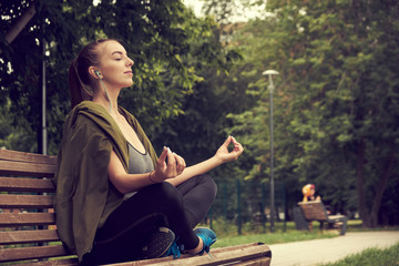 Young Caucasian woman doing yoga in the Park. Sitting in Lotus position.