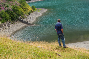 Man who admires the mountain landscape on the alpine lake