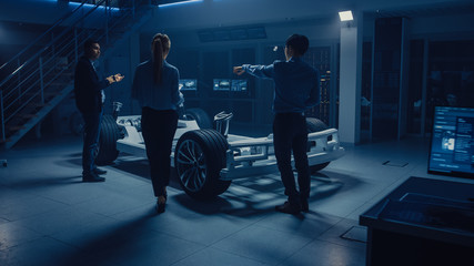 Automobile Engineers Designing Electric Car Platform Chassis, Using Tablet Computers with CAD...