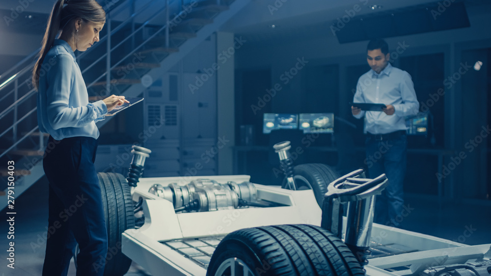 Poster team of automotive engineers working on electric car chassis platform, taking measures, working with
