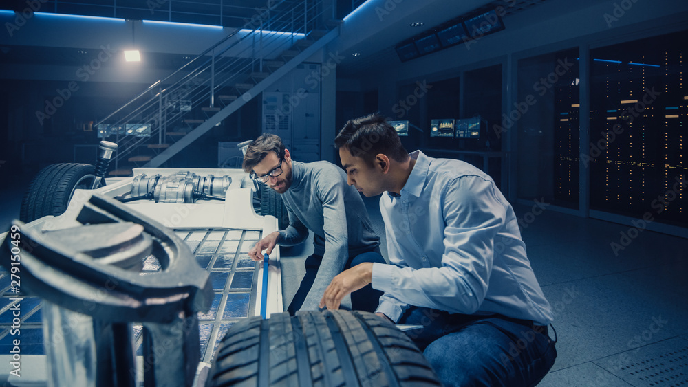 Poster two automotive engineers working on electric car chassis platform, taking measures, working with 3d 