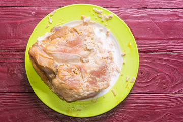 A piece of baked turkey fillet on a plate on a wooden burgundy color background.