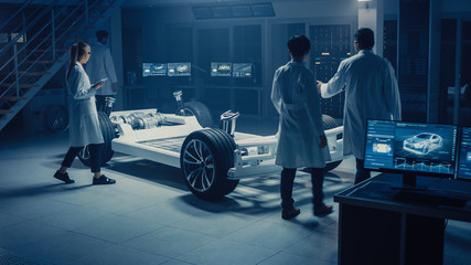 Team of Automotive Engineers and Scientists Discussing, Designing and Working on Electric Car...