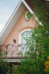 Obraz premium Fragment of a beautiful country house, close-up. Roof, window and balcony with a wrought-iron lattice.