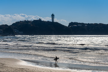 江の島と女性サーファーのシルエット