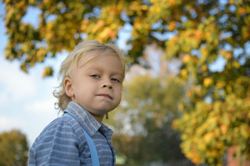 Happy blond boy in autumn park. little child playing in park. boy is in autumn city park. Bright yellow trees. outdoor. nature.