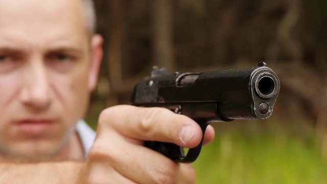 Gun barrel close-up. The man looks at the sight of the gun, making a shot. A man shoots a gun.