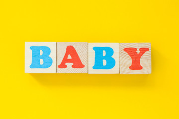 The word "baby" of wooden cubes. Letters on a yellow background. Childhood concept.