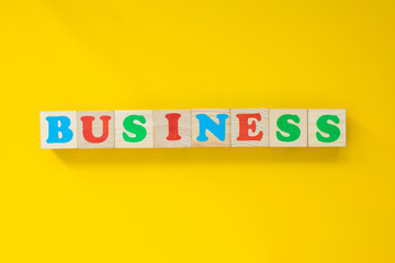 The word "business" from wooden cubes. Letters on a yellow background. Concept business.