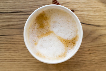 Paper cup of take away coffee on wooden background. Close-up, top view, flat lay, copy space