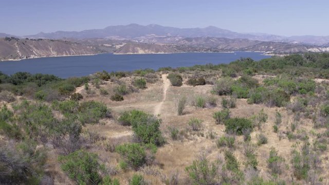 Aerial Drone Shot of a Dirt Trail Leading to a Mountain Lake (Cachuma Lake, California)
