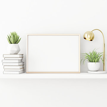 Interior poster mockup with horizontal gold metal frame standing on the table with plants in pots, lamp and pile of books on empty white wall background. 3D rendering, illustration.