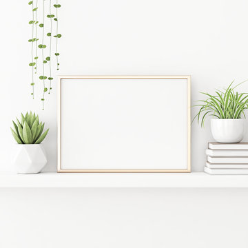 Interior poster mockup with horizontal gold metal frame standing on the table with plants in pots and pile of books on empty white wall background. 3D rendering, illustration.