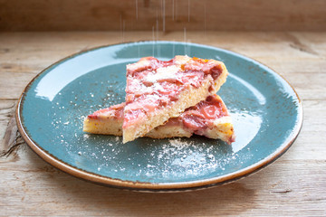 Piece of round strawberry berries tart pie pudding on blue plate on rustic wooden background