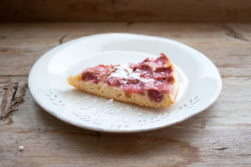 Piece of round strawberry berries tart pie pudding on white plate on rustic wooden background