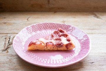 Piece of round strawberry berries tart pie pudding on pink plate on rustic wooden background