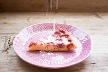 Piece of round strawberry berries tart pie pudding on pink plate on rustic wooden background