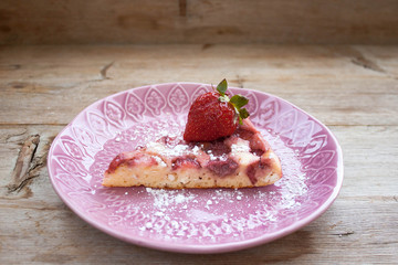 Piece of round strawberry berries tart pie pudding on pink plate on rustic wooden background