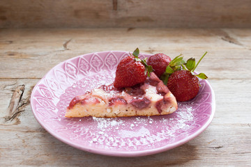 Piece of round strawberry berries tart pie pudding on pink plate on rustic wooden background