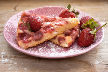 Piece of round strawberry berries tart pie pudding on pink plate on rustic wooden background