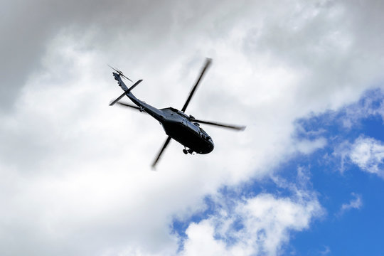 a military helicopter flies in a cloudy sky