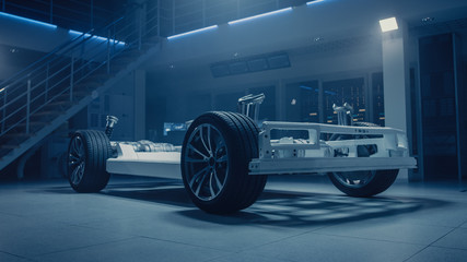 Fototapeta na wymiar Concept of Authentic Electric Car Platform Chassis Prototype Standing in Industrial Machinery Design Laboratory. Hybrid Axel Frame include Wheels, Suspension, Engine, Brakes and Battery. 