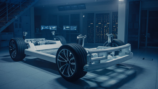 Concept of Authentic Electric Car Platform Chassis Prototype Standing in Industrial Machinery Design Laboratory. Hybrid Axel Frame include Wheels, Suspension, Engine, Brakes and Battery. 