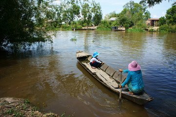 Vietnamese woman transport little girl go to school by wooden boat