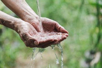 Closeup water flow to hand of women for nature concept on the garden background.