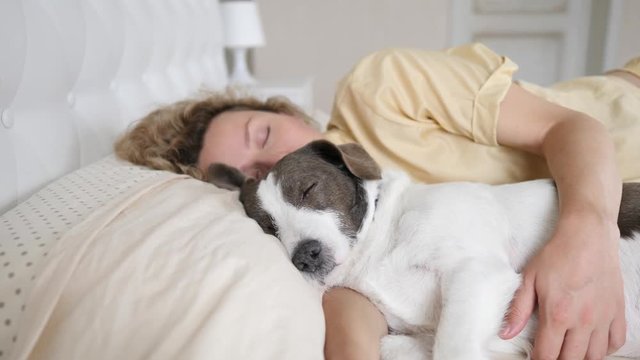 Young Woman Sleeping With Her Pet Dog In Bed
