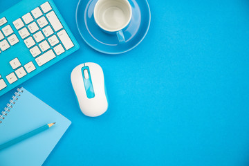 Business office table with business objects of keyboard,mouse,pencil,paper note and coffee cup on blue background