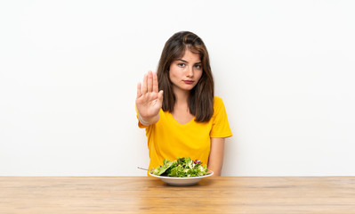 Caucasian girl with salad making stop gesture with her hand