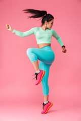 Concentrated young sports fitness woman isolated over pink wall background make exercises.