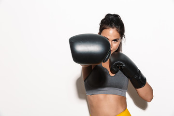 Gorgeous young sports fitness woman boxer isolated over white wall background make boxing exercises with gloves.