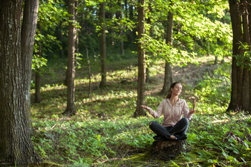 Beautiful woman meditating in the forest on a sunny morning