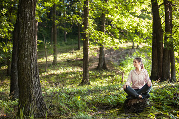 Fototapeta premium Beautiful woman meditating in the forest on a sunny morning