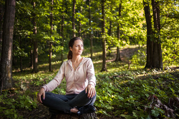 Obraz premium Beautiful woman meditating in the forest on a sunny morning